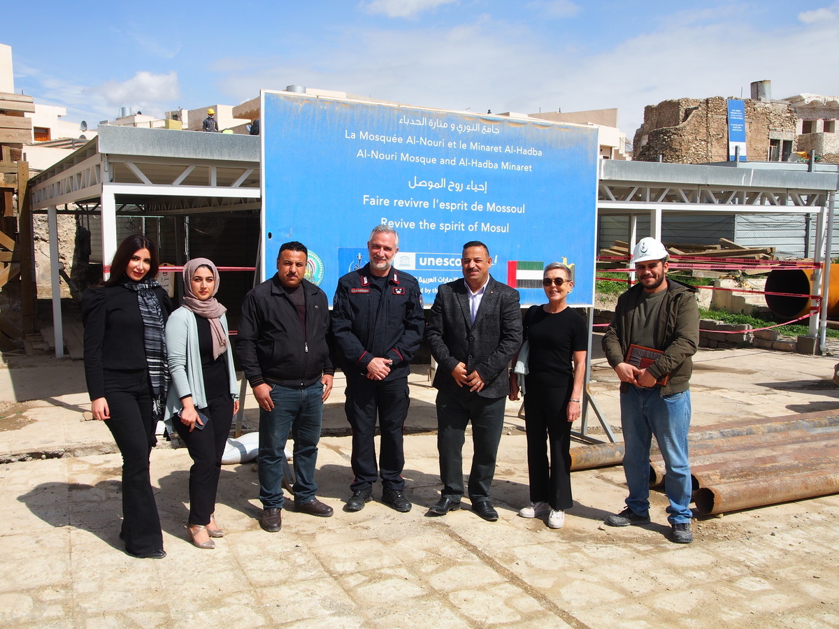 A group of people posing for a photo in front of a sign

Description automatically generated