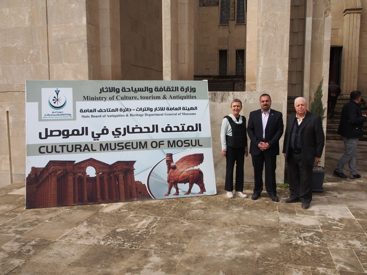 A group of people standing next to a sign

Description automatically generated with medium confidence